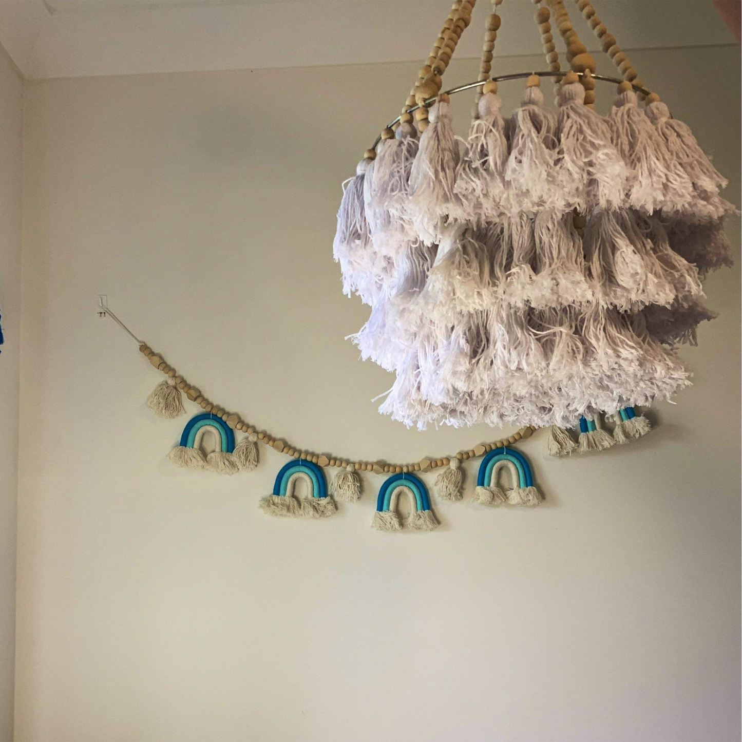 A hanging tassel mobile with beaded tassels in white, with a natural wooden ring at the top for hanging.