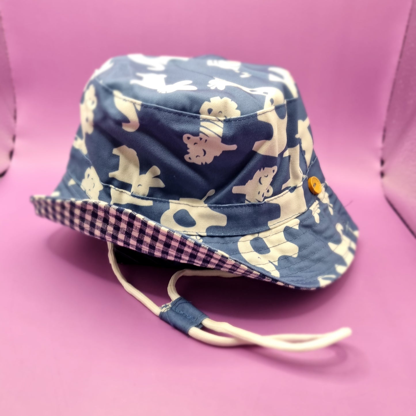 Toddler sun hat with animal pattern. Blue gingham pattern underside. Adjustable strap.