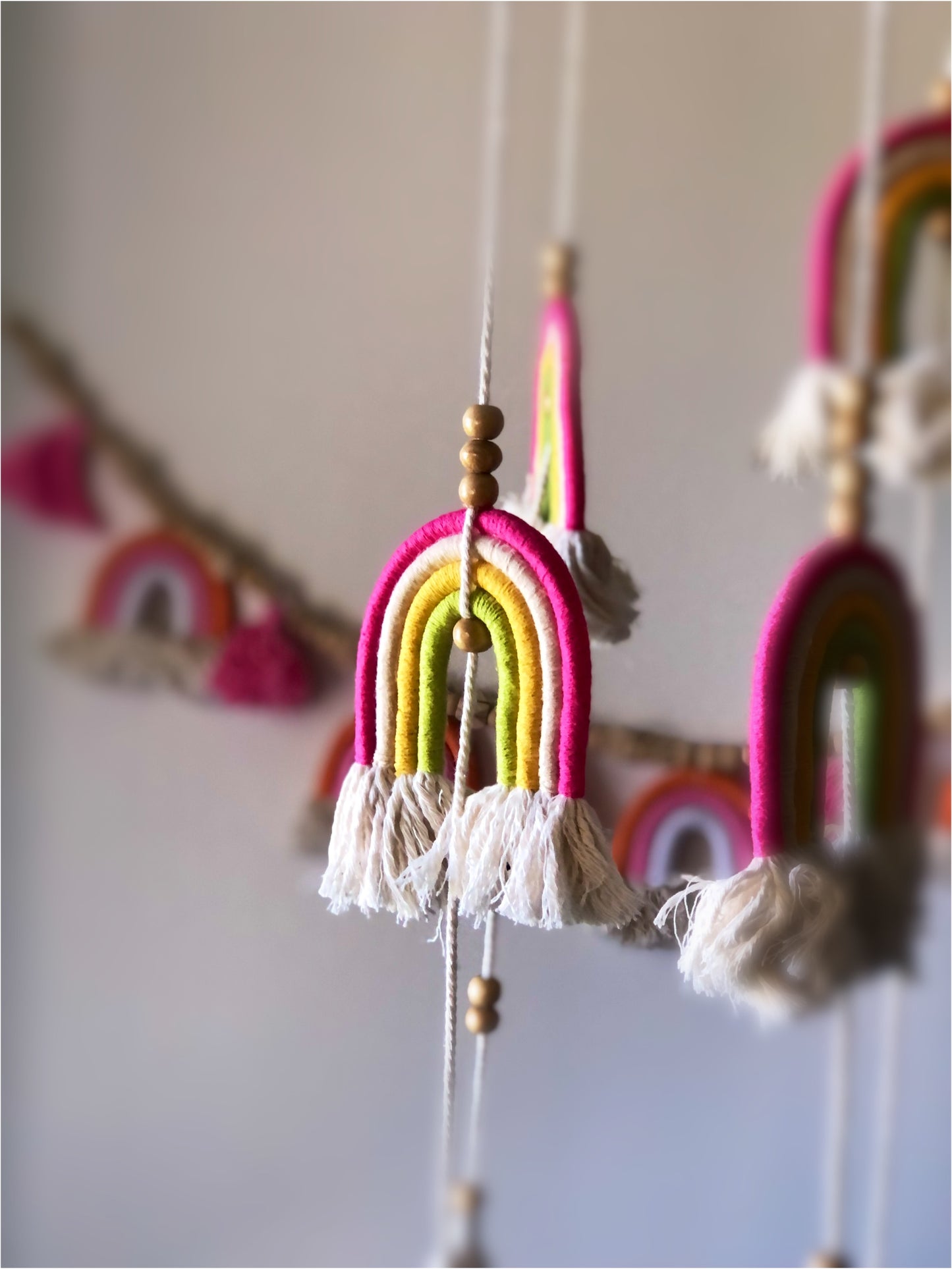 Pink, yellow and green design. Long mobile featuring rainbows and tassels