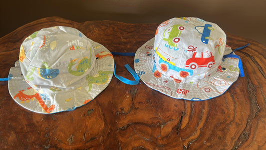 Two reversible children's hats, one with a car pattern and the other with a construction vehicle pattern. Wide brim and summer fabric