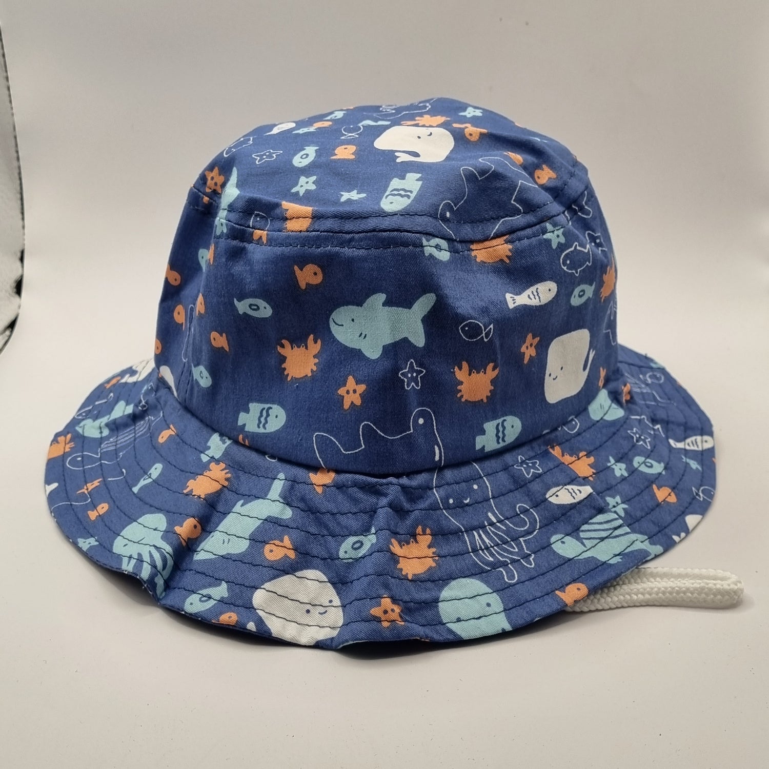 Blue children's hat with ocean-themed pattern. Adjustable under the chin strap. 