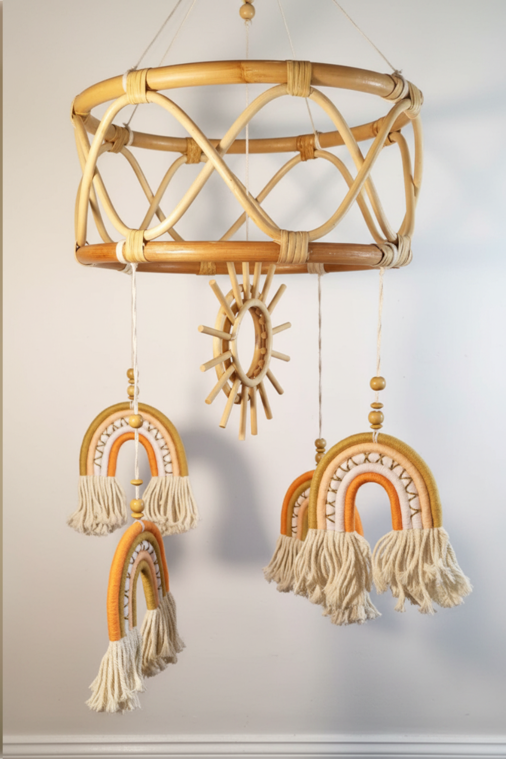 Boho rattan baby mobile in orange and gold colourway with wooden sun centrepiece and cream macrame tassels — nursery decor Australia