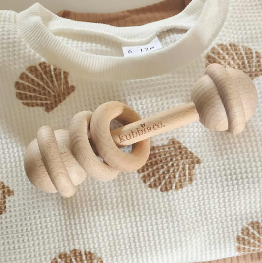 A wooden teether with a series of rounded rings on a handle.