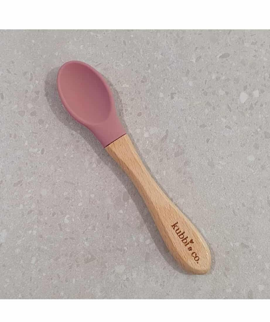 A baby spoon with a pink silicone head and beech wood handle, with the brand 'Kubbi & co' inscribed on the handle.